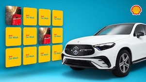 Weisser Mercedes-SUV rechts im Bild, links daneben ein gelbes Shell-Car-Wash-Memory-Spiel mit aufgedeckten Autowasch-Karten vor blauem Hintergrund, Shell-Logo oben rechts in der Ecke.