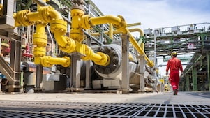 Ein Arbeiter in roter Schutzkleidung geht in einer industriellen Umgebung