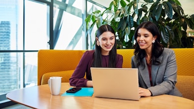 Team arbeitet gemeinsam an einem Laptop in einer modernen Büroumgebung