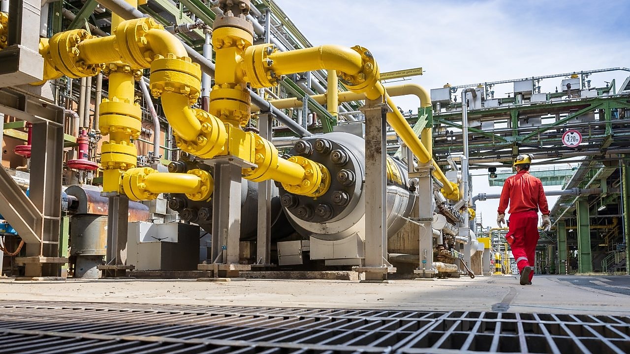 Ein Arbeiter in roter Schutzkleidung geht in einer industriellen Umgebung