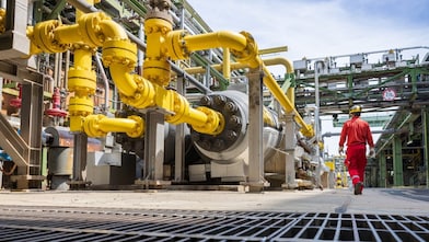 Ein Arbeiter in roter Schutzkleidung geht in einer industriellen Umgebung