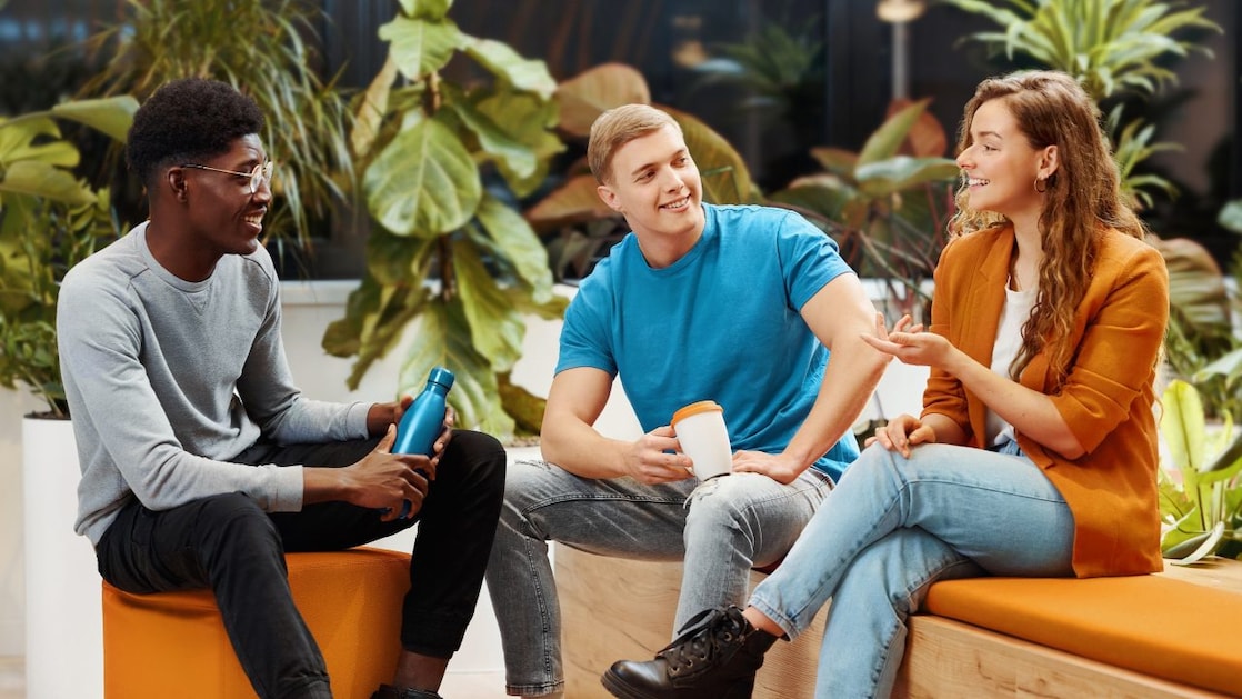Three colleagues discuss in a bright and modern office environment