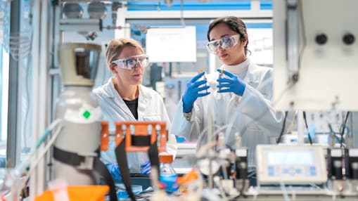 Laborpersonal arbeitet gemeinsam an Geräten in einem technischen Labor