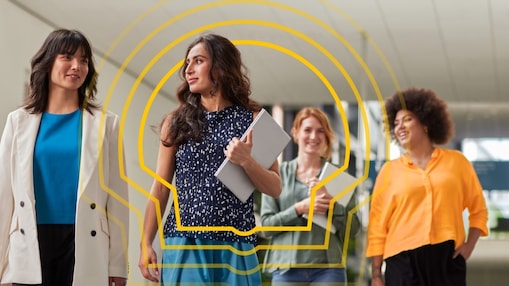 Vier Personen gehen selbstbewusst in einem modernen, gut beleuchteten Gebäude.