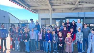 Gruppenfoto von Schülerinnen und Betreuenden vor einem Industriegebäude bei sonnigem Wetter, aufgenommen während des Girls’ und Boys’ Day.