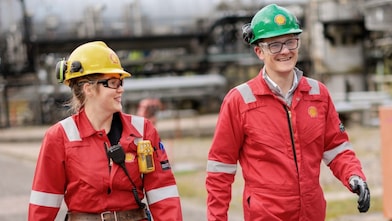 Two workers in red overalls walking in an industrial environment 