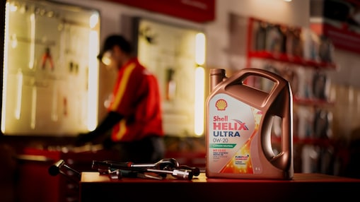 Das Shell Helix Ultra Motoröl sitzt im Vordergrund, Werkzeuge und Mechanik im Hintergrund.