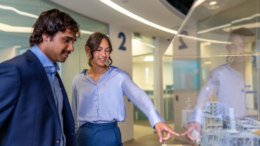 Personen betrachten gemeinsam ein Modell hinter einer Glasscheibe und diskutieren darüber