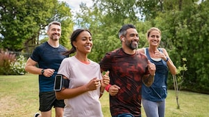 Vier Personen joggen in einem Park, alle wirken energiegeladen