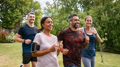 Vier Personen joggen in einem Park, alle wirken energiegeladen