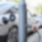 Eine Hand schließt ein Stromkabel an eine Ladestation neben einem Auto auf einer Straße an.