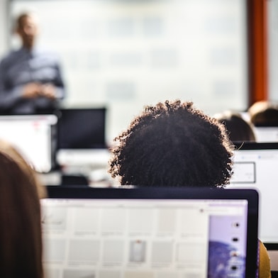 Ein Klassenzimmer von hinten mit Schülern, die an Computern arbeiten.