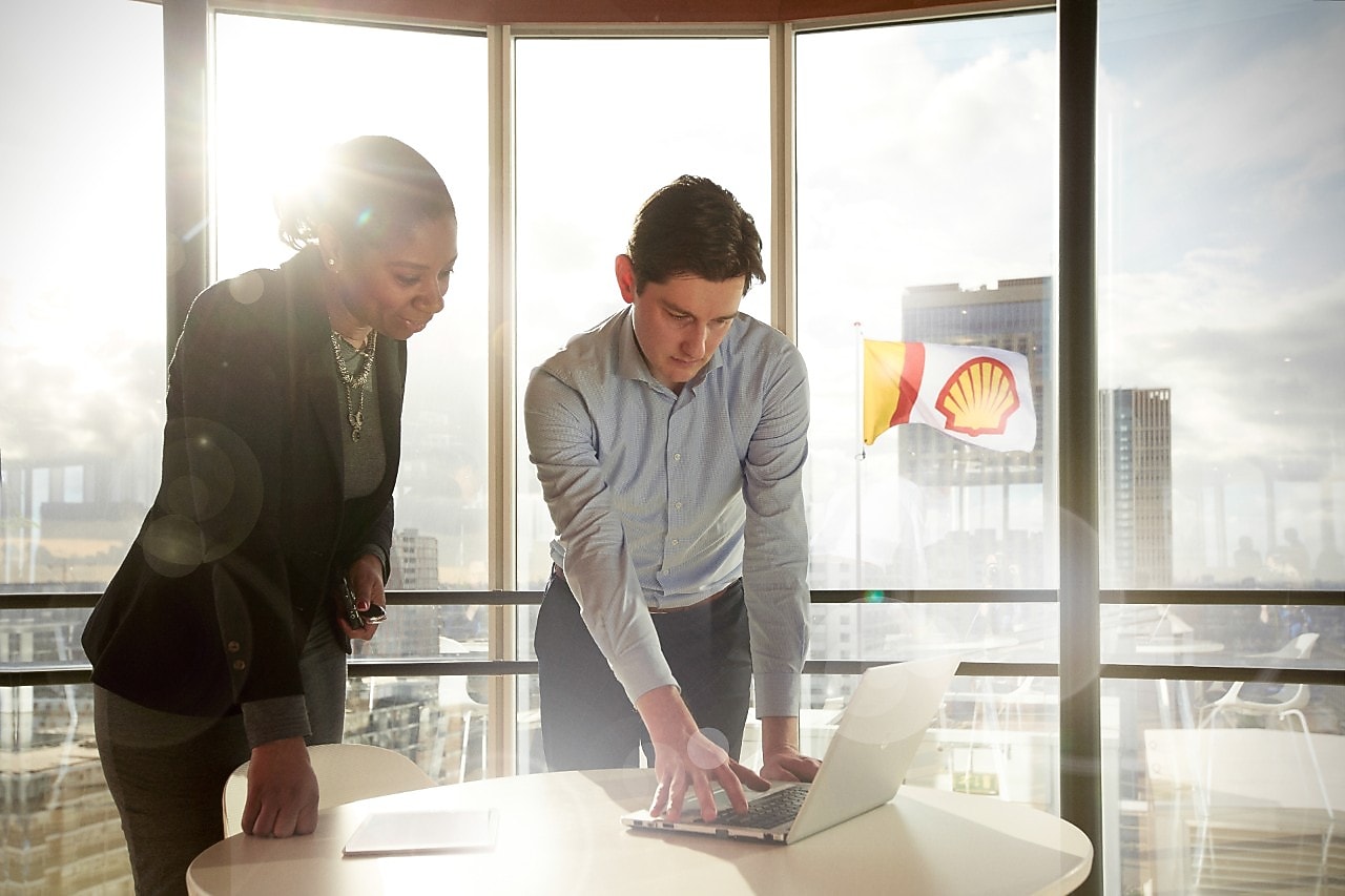 Zwei Personen auf einen Laptop blickend