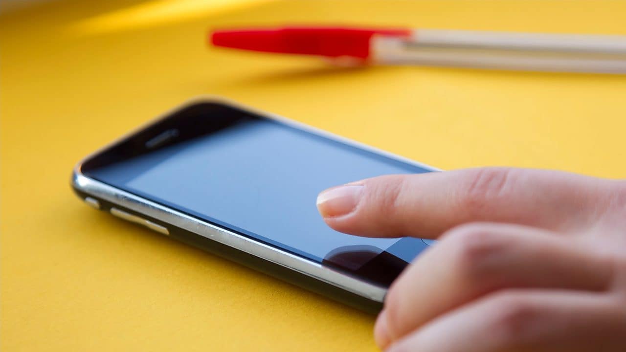 Ein Smartphone auf dem Tisch, neben einem roten Kugelschreiber