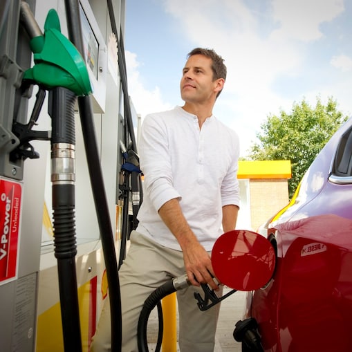 Mann mit Auto vor Zapfsäule an Shell Station