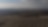 Eine offene, karge Landschaft mit kahlen Bäumen und nebeligen Hügeln im Hintergrund. Der Himmel ist bewölkt.