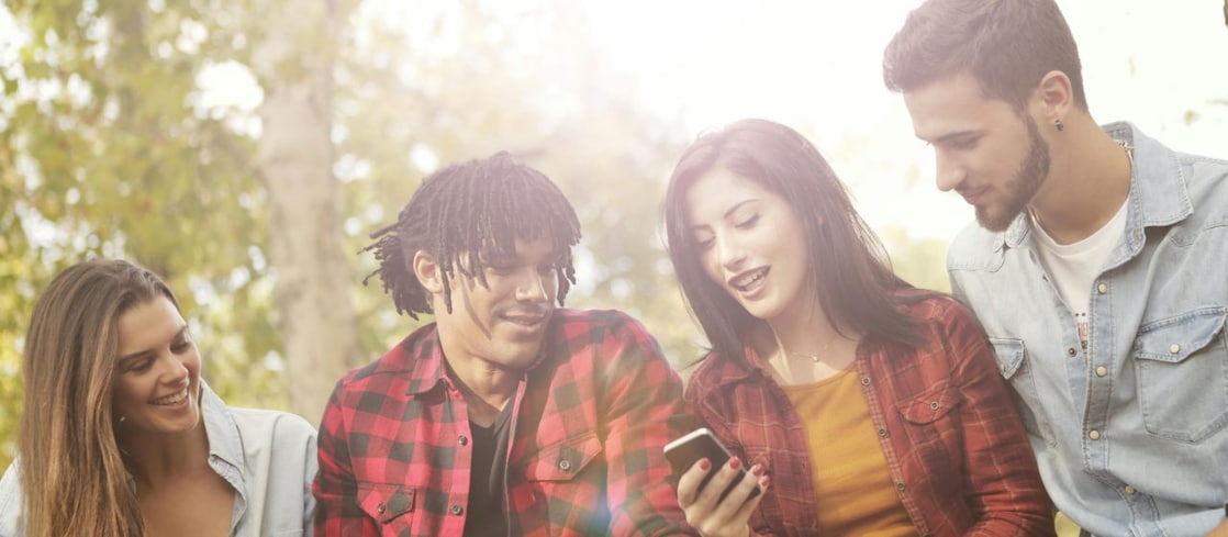Stockbild einer Gruppe junger Leute, die gemeinsam auf ein Handy schauen