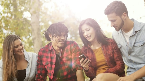 Stockbild einer Gruppe junger Leute, die gemeinsam auf ein Handy schauen