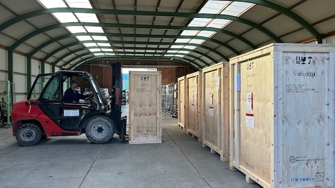 Forklift transporting a large electrolyser stack crate in a warehouse before shipment to the Shell Rheinland hydrogen project.