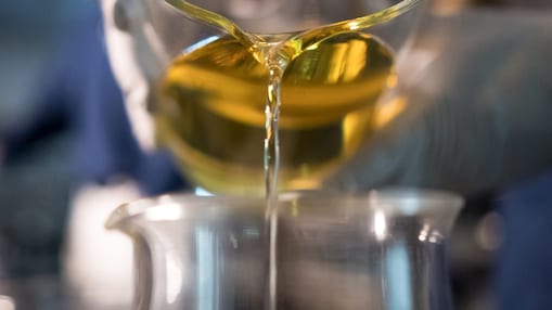 Baseoil: Ein hochwertiges Grundöl. Öl wird im Labor von einem Glas in ein anderes gegossen.