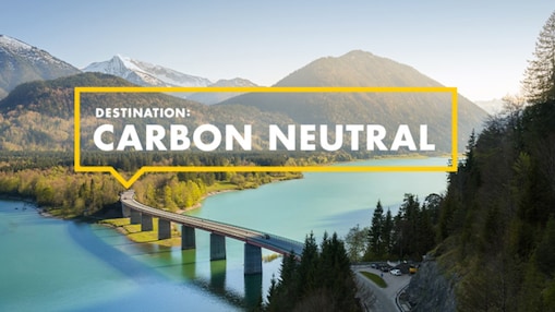 Destination Carbon Neutral. Straßenbrücke über Fluss in natürlicher Berglandschaft.