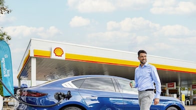 Mann nutzt die Ladezeit an Shell Recharge Ultraschnell-Ladesäule für einen Kaffe aus dem Shell Cafe