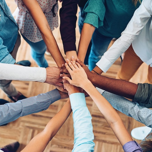 Colleagues with all hands in showing teamwork