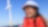 Lächelnde Frau mit einem Helm vor einem Offshore-Windrad