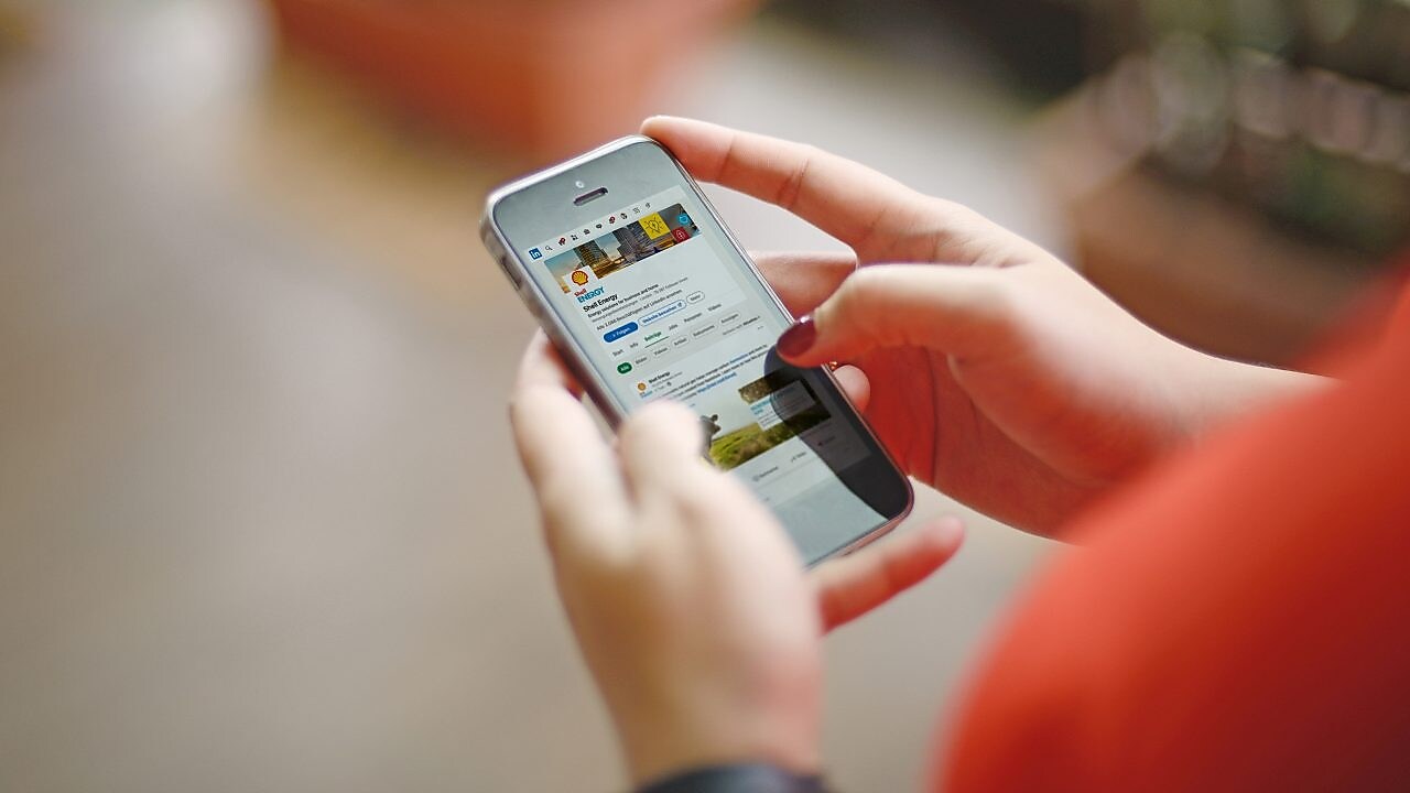 Jemand hält ein Smartphone mit der LinkedIn Seite von Shell Energy