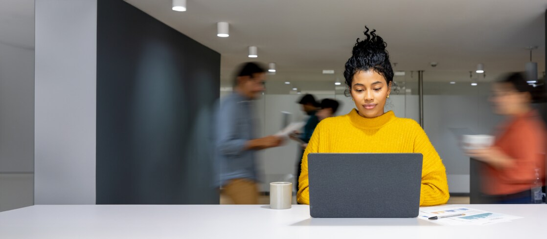 Ein belebtes Büro mit einer Frau an einem Laptop