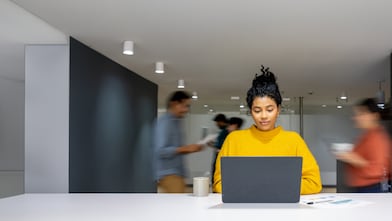 Ein belebtes Büro mit einer Frau an einem Laptop
