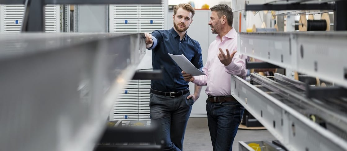 Zwei Mitarbeiter besprechen sich in der Produktionshalle ihres Unternehmens