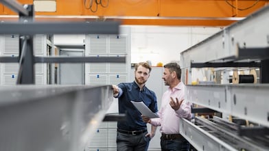 Zwei Mitarbeiter besprechen sich in der Produktionshalle ihres Unternehmens