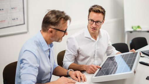 Eine Person erklärt einer anderen eine Solarzelle