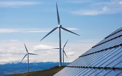 3 Winräder und 1 Solaranlage in einem Gebirge.