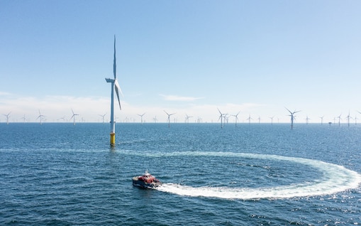 Ein Boot fährt um ein Offshore Windrad herum