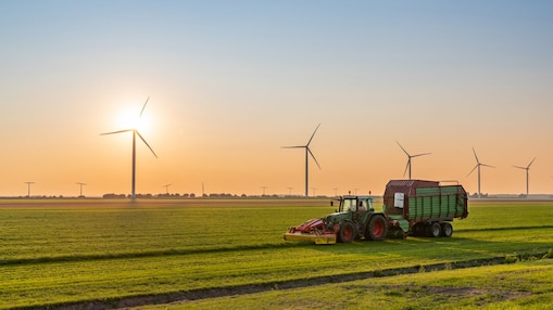 Traktor fährt über ein feld mit windrädern
