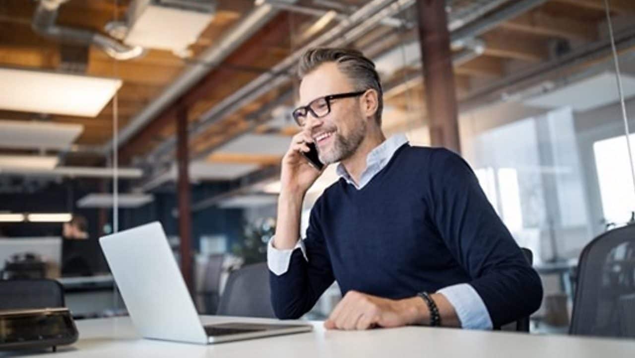 Mann sitzt am Schreibtisch und telefoniert