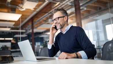 Mann sitzt am Schreibtisch und telefoniert