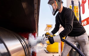 Ein Mann tankt LNG an einer Shell Station und trägt dabei eine Schutzausrüstung.