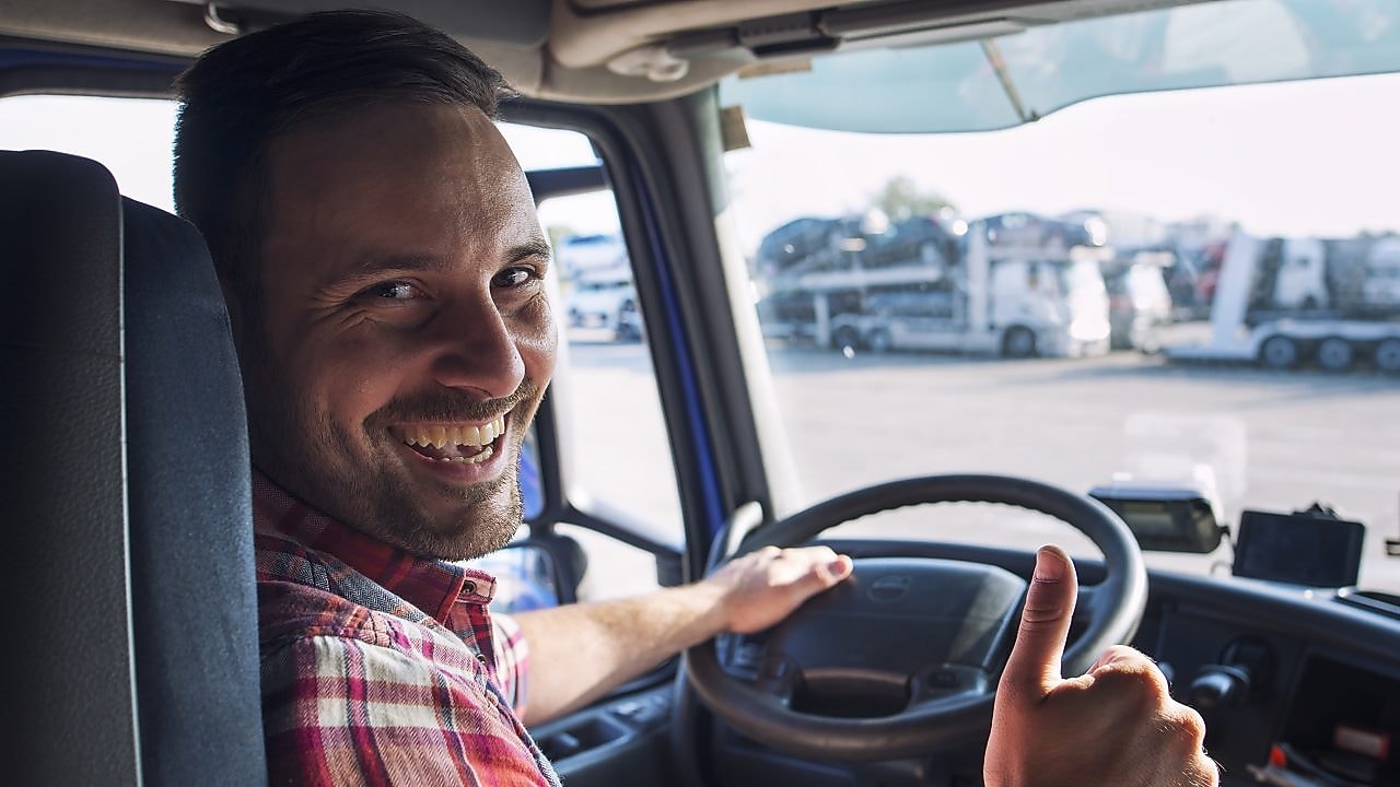Freundlicher LKW Fahrer guckt in die Kamera
