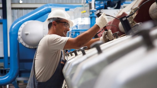 Techniker führt Wartungsarbeiten an einem stationären Gasmotor in einer industriellen Stromerzeugungsanlage durch.