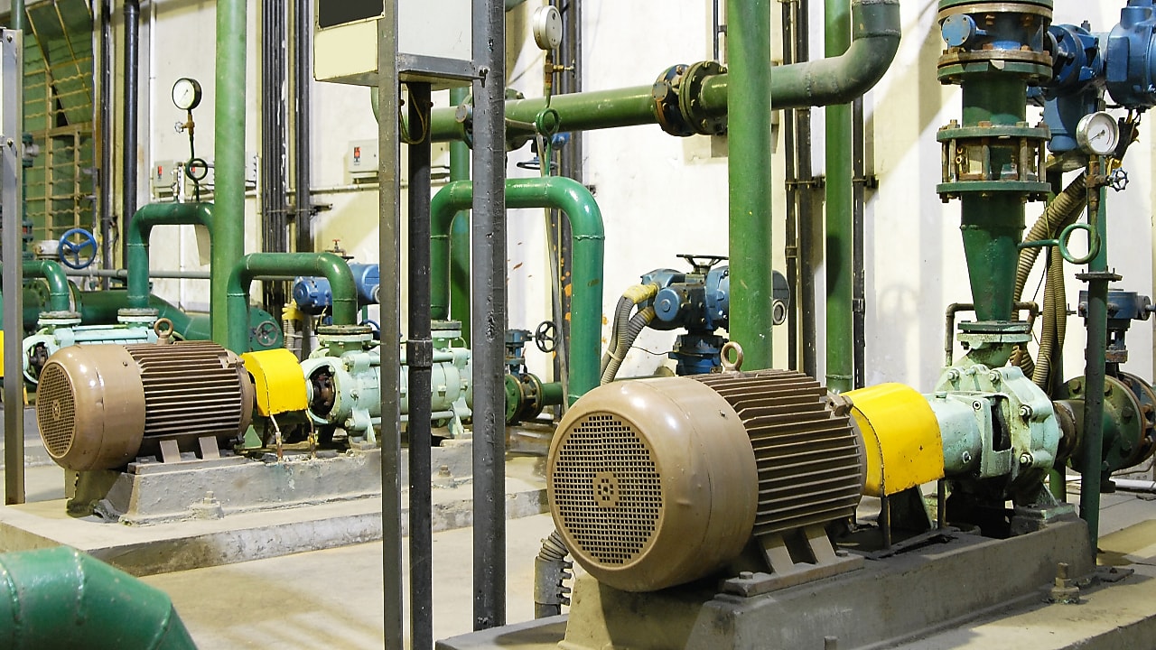 Industrieller Maschinenraum mit Pumpen, Motoren und grünen Rohrleitungen zur Stromerzeugung.