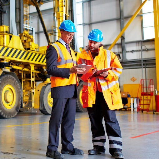 Zwei Bauarbeiter mit Schutzhelmen und Warnwesten