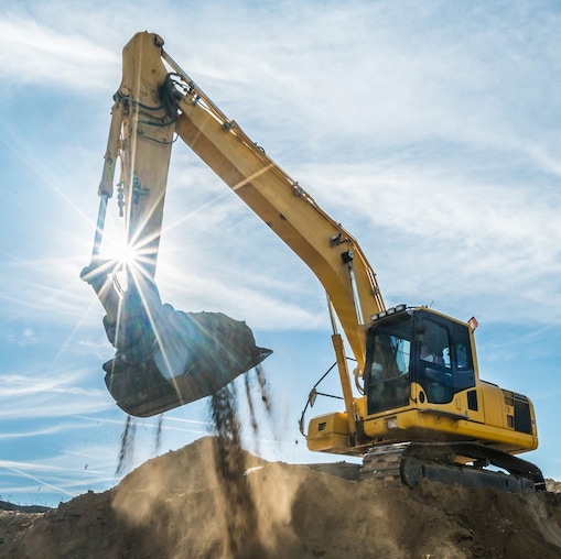Bagger, der Erde in einen Muldenkipper kippt