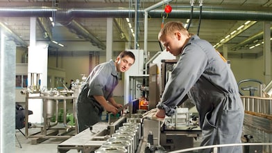 Industriearbeiter bedienen eine automatisierte Produktionslinie zur Montage von Metallkomponenten in einer Fertigungsanlage zur Steigerung der Effizienz und Schmierstoffleistung