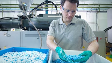 Industriearbeiter prüft Kunststoffgranulat in einer Produktionsanlage zur Qualitätskontrolle und Effizienz von Schmierstoffen