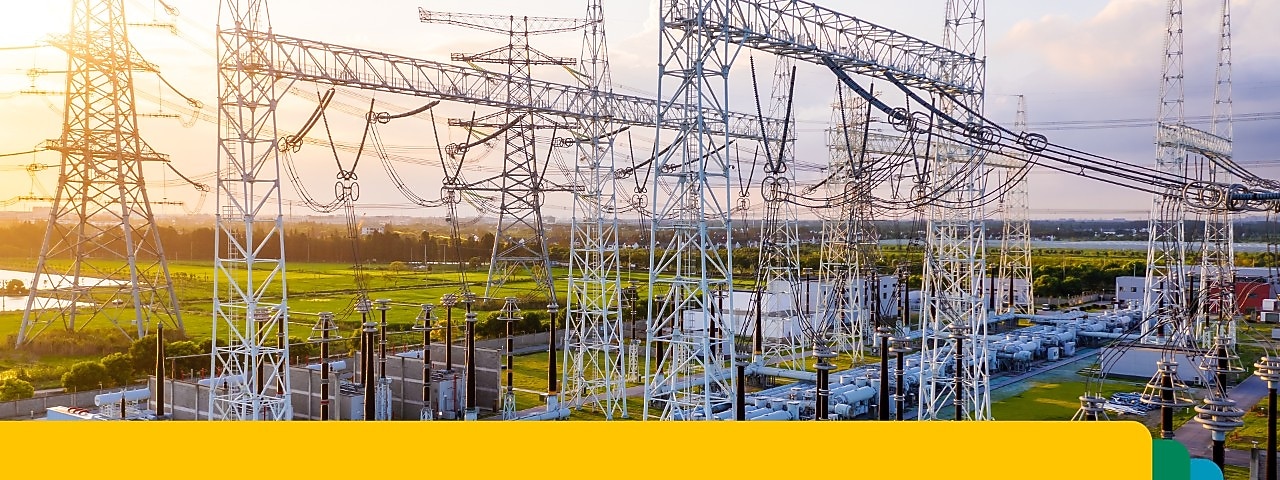 Umspannwerk mit miteinander verbundenen Hochspannungsleitungen und -geräten bei Sonnenuntergang.