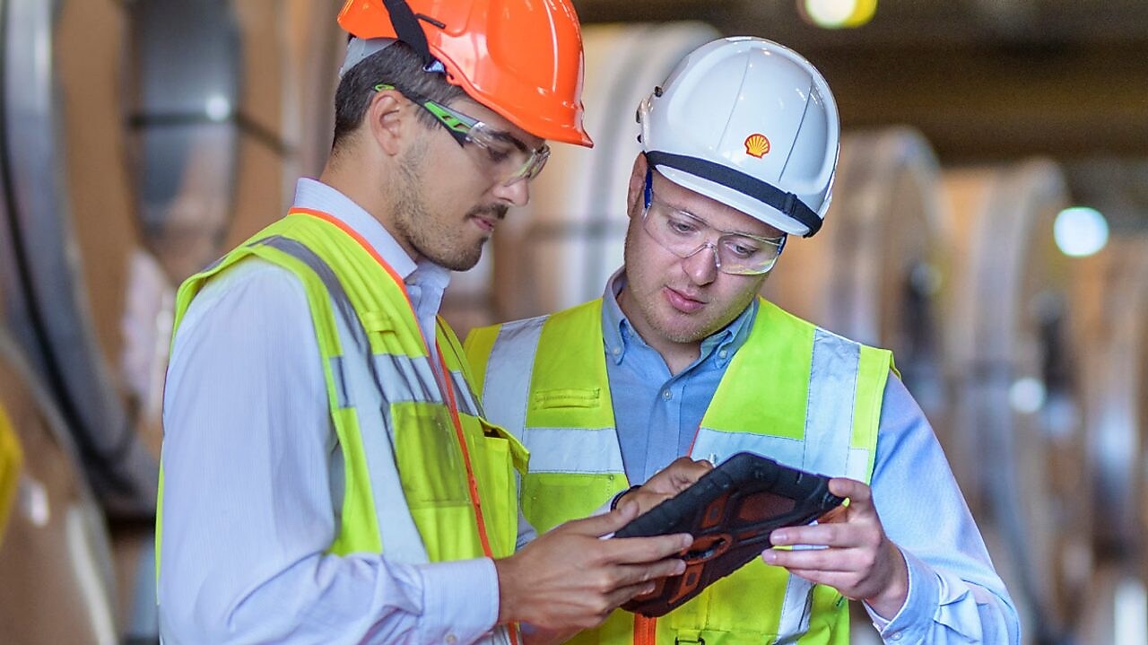 Shell Mitarbeiter berät einen Industriearbeiter vor Ort