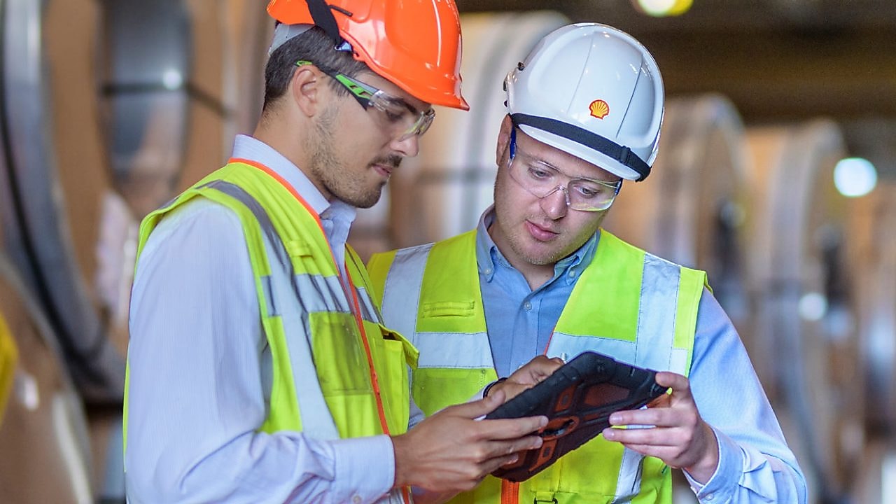 Shell Mitarbeiter berät einen Industriearbeiter vor Ort